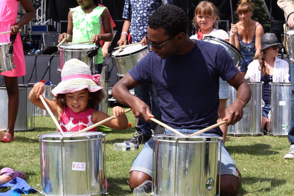 A father and daughter playing with steel drums.