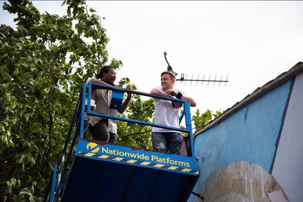 Two artists: Tony (left) and Nath (right) stood on a cherrypicker while working on the mural